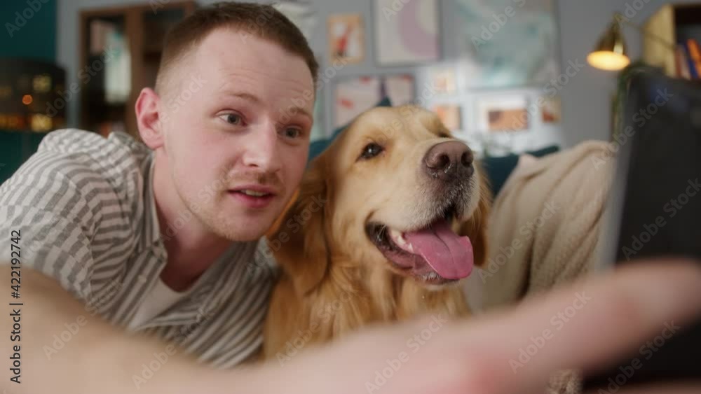 British redhead man together with dog retriever making selfie photo or video call on front camera smartphone. Positive young student man conference call with pet for blog. British redhead man together with dog retriever making selfie photo or video call on front camera smartphone. Positive young student man conference call with pet for blog.