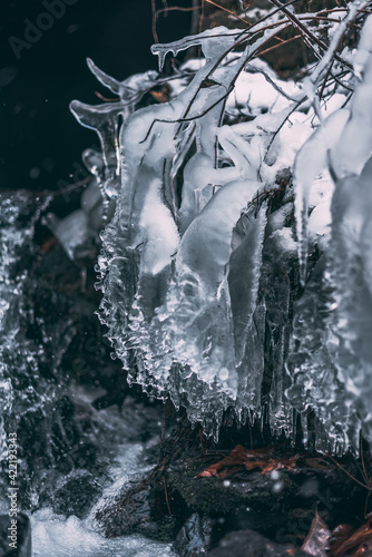 Ice and icicles hanging from a rock along a creek