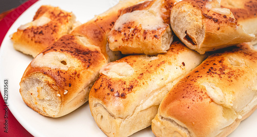 Pão de alho ( pão-com-alho ) assado recheado com queijo servido em um prato branco. O pão de alho no Brasil é tradicionalmente servido durante um churrasco.	 photo