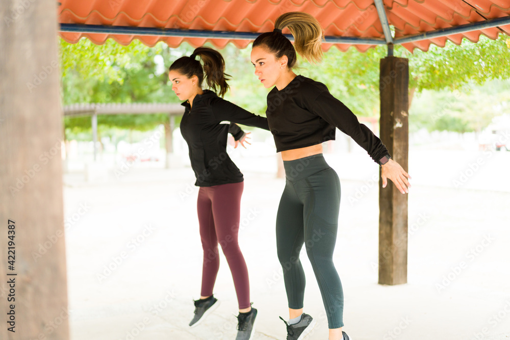 Two women with a healthy lifestyle jumping in the park