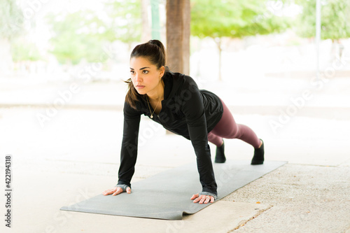 Gorgeous latin woman in her 30s doing a plank in the park © AntonioDiaz