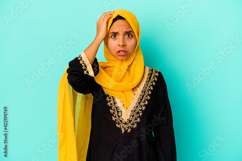 Young muslim woman isolated on blue background being shocked, she has remembered important meeting.