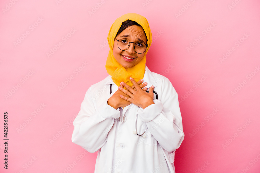 Young doctor muslim woman isolated on pink background has friendly expression, pressing palm to chest. Love concept. Young doctor muslim woman isolated on pink background has friendly expression, pressing palm to chest. Love concept.