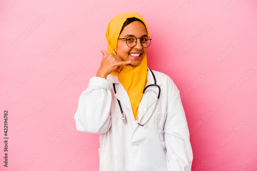 Young doctor muslim woman isolated on pink background showing a mobile phone call gesture with fingers. Young doctor muslim woman isolated on pink background showing a mobile phone call gesture with fingers.
