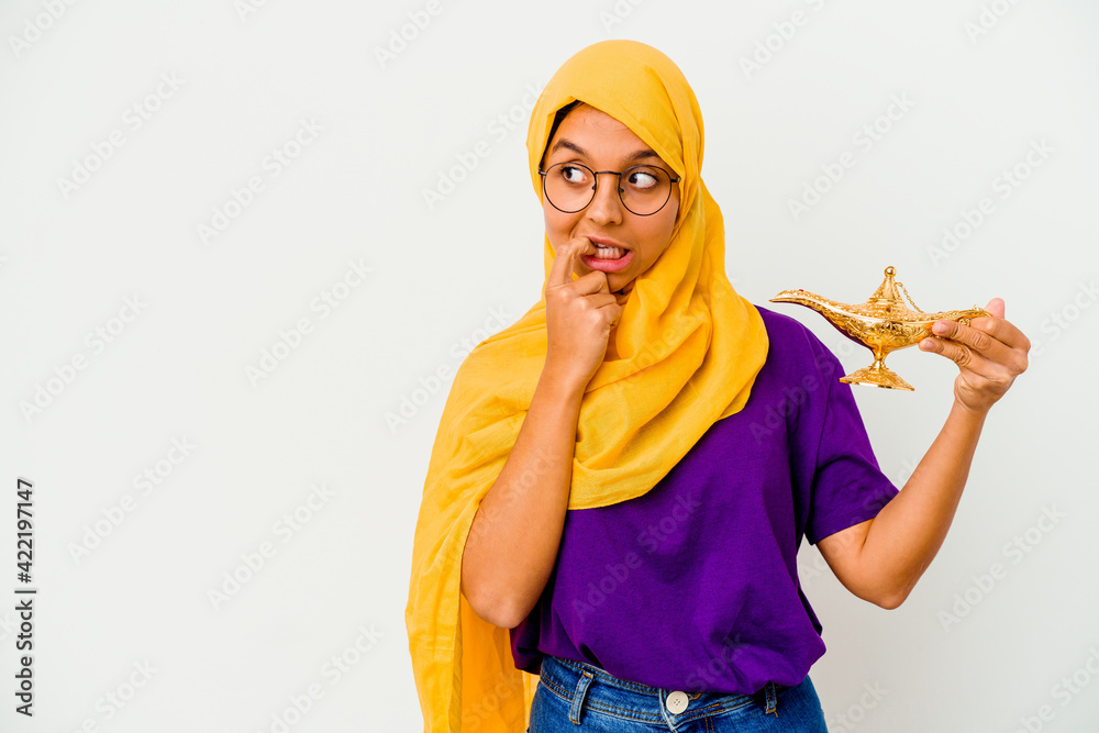 Young muslim woman holding a lamp isolated on white background relaxed thinking about something looking at a copy space.