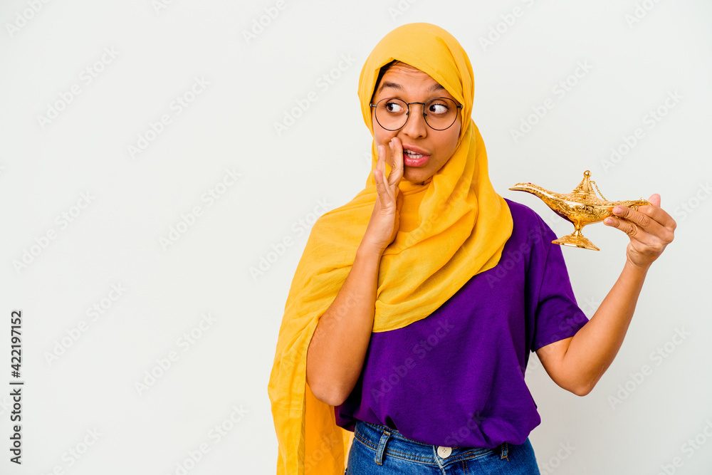 Young muslim woman holding a lamp isolated on white background is saying a secret hot braking news and looking aside Young muslim woman holding a lamp isolated on white background is saying a secret hot braking news and looking aside