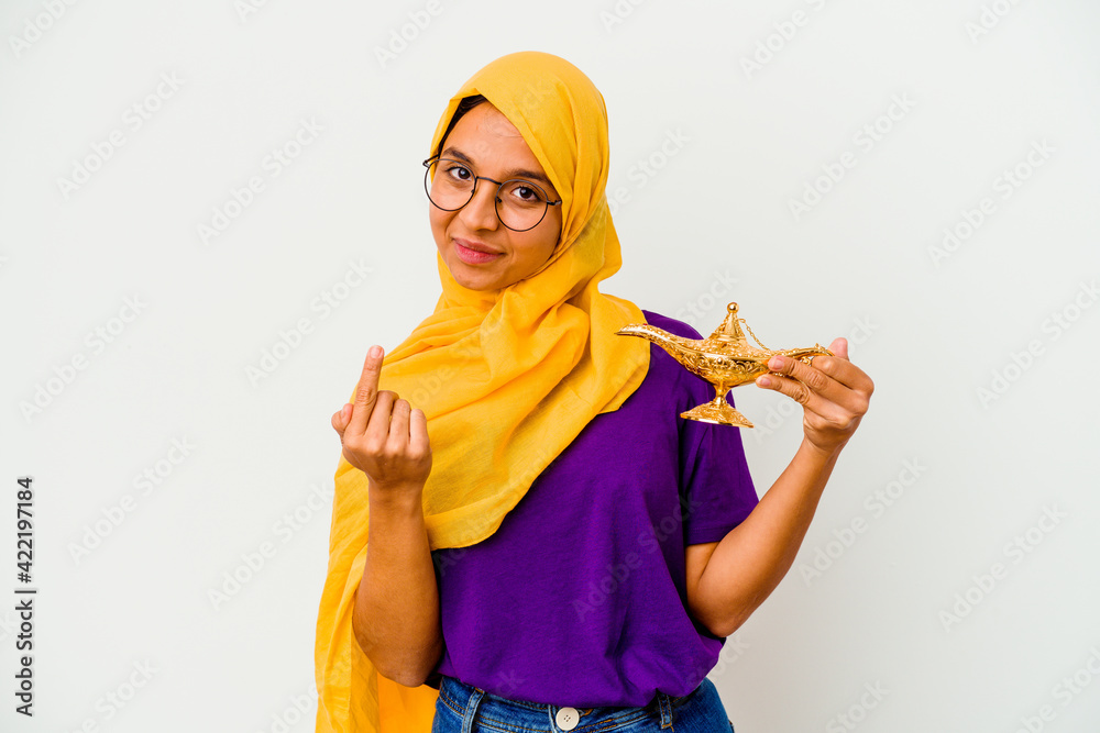 Young muslim woman holding a lamp isolated on white background pointing with finger at you as if inviting come closer. Young muslim woman holding a lamp isolated on white background pointing with finger at you as if inviting come closer.