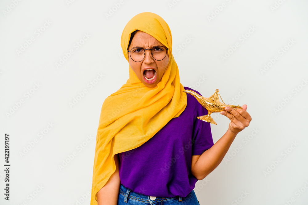 Young muslim woman holding a lamp isolated on white background screaming very angry and aggressive. Young muslim woman holding a lamp isolated on white background screaming very angry and aggressive.