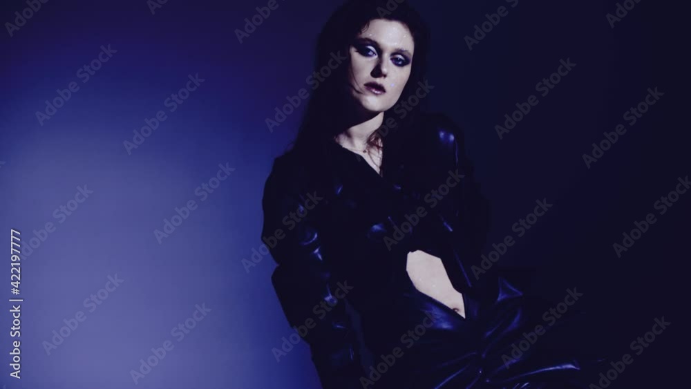 Dark and long hair woman posing in the studio. Young attractive model girl wearing black dress dancing in the studio.