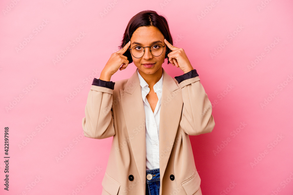 Young business mixed race woman isolated on pink background focused on a task, keeping forefingers pointing head.