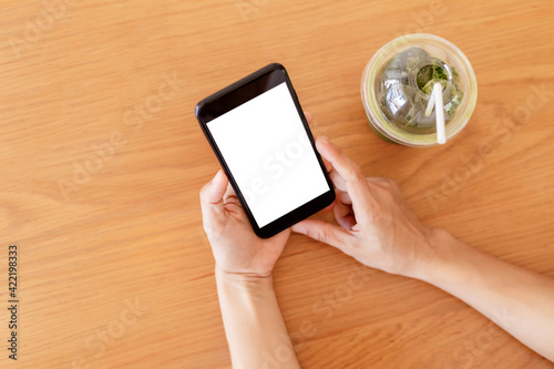Close up hands of woman using mobile phone, cell phone in coffee shop. Hands of women holding blank empty screen smart phone in cafe. Women relax with mobile phone sit in restaurant