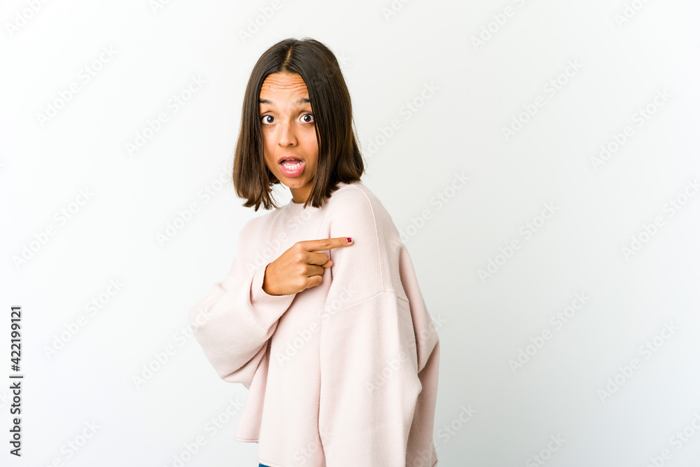 Young mixed race woman smiling and pointing aside, showing something at blank space. Young mixed race woman smiling and pointing aside, showing something at blank space.