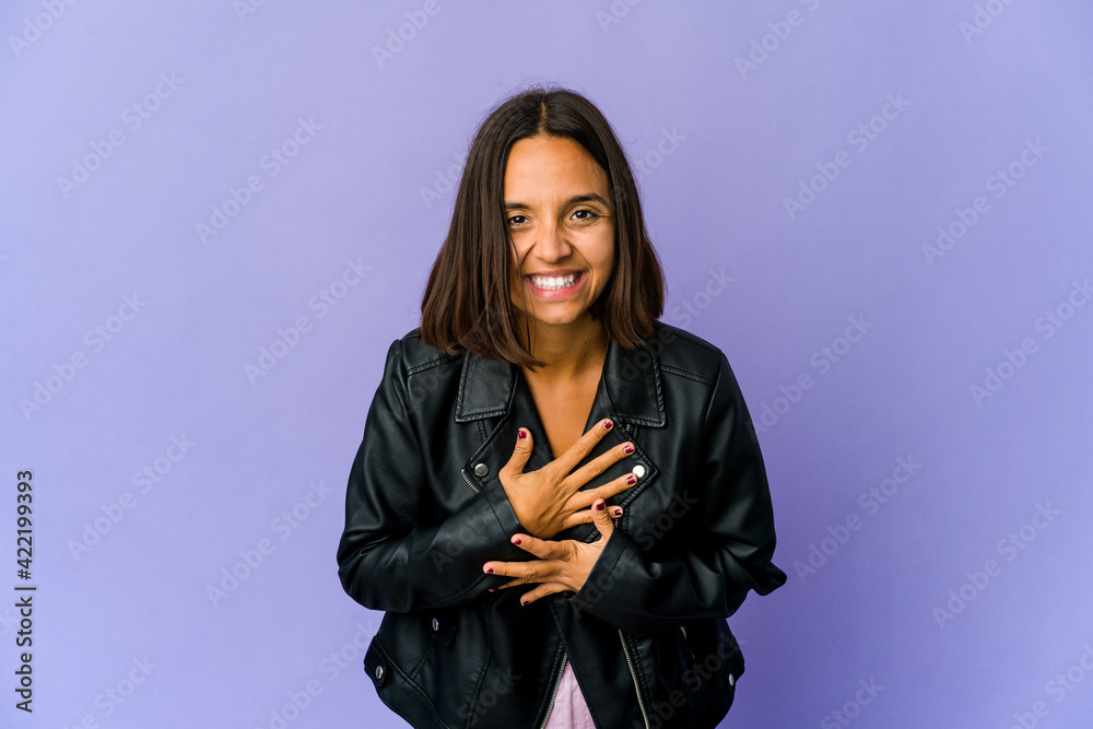Young mixed race woman laughs out loudly keeping hand on chest. Young mixed race woman laughs out loudly keeping hand on chest.