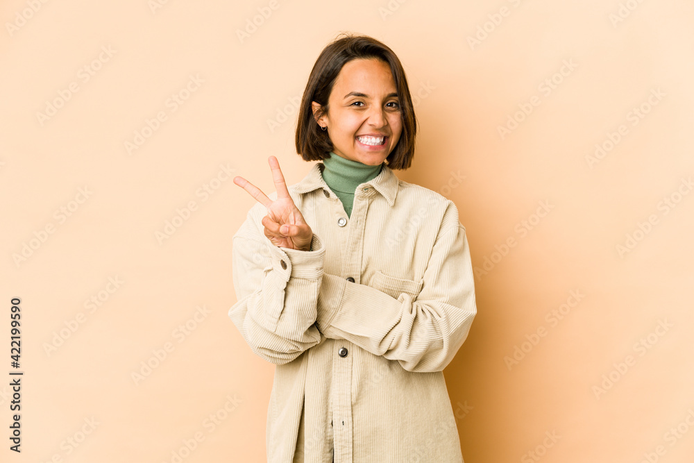 Young hispanic woman isolated joyful and carefree showing a peace symbol with fingers. Young hispanic woman isolated joyful and carefree showing a peace symbol with fingers.