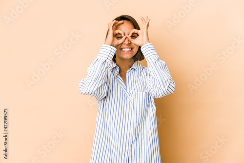 Young hispanic woman isolated excited keeping ok gesture on eye.