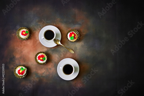 Couple of cup of fresh black strong coffee on saucers with yellow spoon and sweet cream cake in basket on big dark background. Top view, flat lay