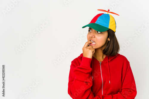 Young hispanic woman wearing a cap with propeller isolated relaxed thinking about something looking at a copy space.
