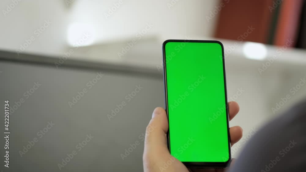 Handheld Camera: Point of View of Man at Modern Room Sitting on a Chair Using Phone With Green Mock-up Screen Chroma Key Surfing Internet Watching Content Videos Blogs Tapping on Center Screen Handheld Camera: Point of View of Man at Modern Room Sitting on a Chair Using Phone With Green Mock-up Screen Chroma Key Surfing Internet Watching Content Videos Blogs Tapping on Center Screen
