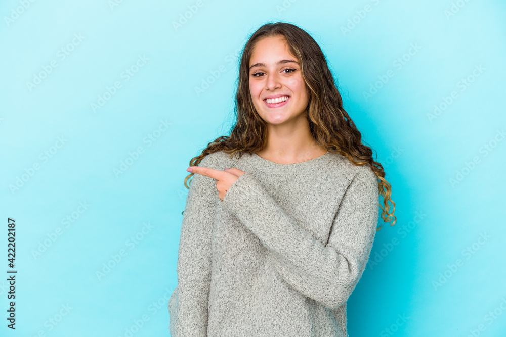 Young caucasian curly hair woman isolated smiling and pointing aside, showing something at blank space. Young caucasian curly hair woman isolated smiling and pointing aside, showing something at blank space.