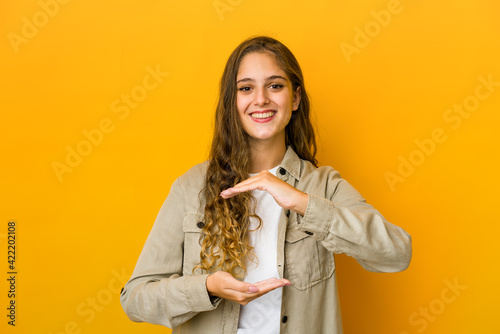 Young caucasian woman holding something with both hands, product presentation.