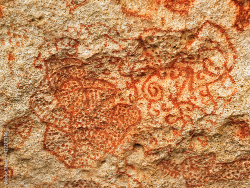 Carib or Arawak cave paintings in red dye on a rock wall, authentic pre-Columbian art in Caribbean Islands.