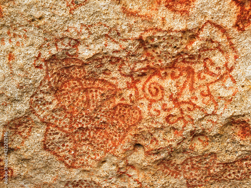 Carib or Arawak cave paintings in red dye on a rock wall, authentic pre-Columbian art in Caribbean Islands. photo