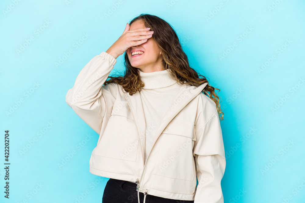 Young caucasian curly hair woman isolated covers eyes with hands, smiles broadly waiting for a surprise. Young caucasian curly hair woman isolated covers eyes with hands, smiles broadly waiting for a surprise.