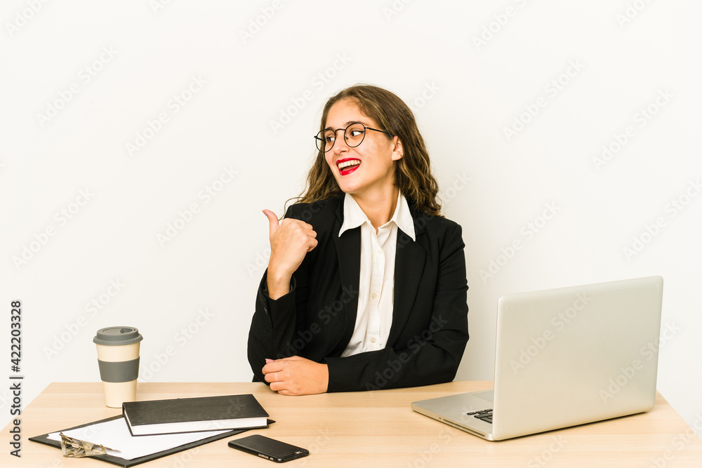 Young caucasian business woman working on her desktop isolated points with thumb finger away, laughing and carefree. Young caucasian business woman working on her desktop isolated points with thumb finger away, laughing and carefree.