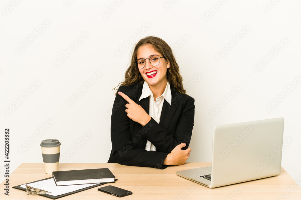 Young caucasian business woman working on her desktop isolated smiling and pointing aside, showing something at blank space. Young caucasian business woman working on her desktop isolated smiling and pointing aside, showing something at blank space.