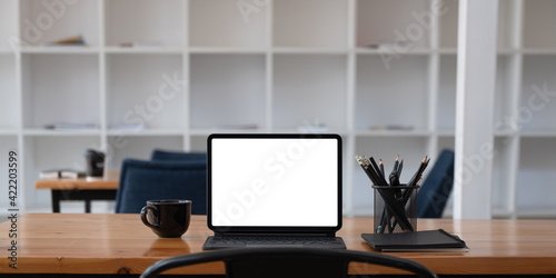 Cropped shot of workplace with tablet blank screen and office supplies in simple workspace