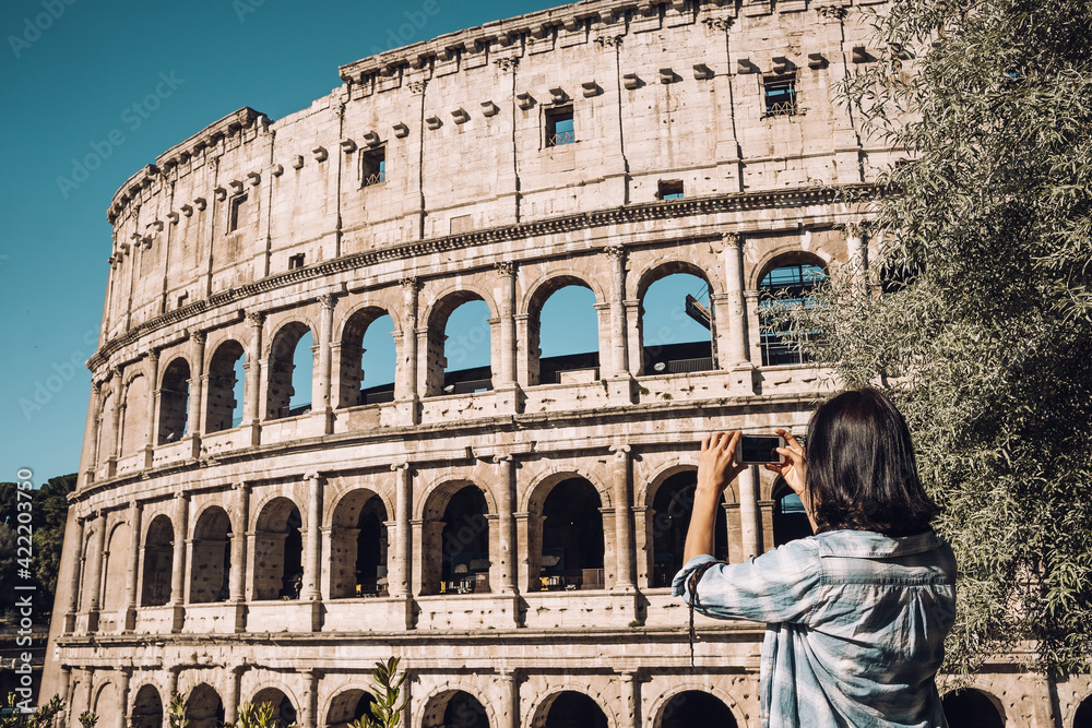 Young woman take a picture of Colosseum by smartphone in Rome