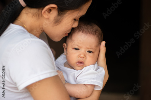 Young Asian mother kissing and holding little daughter in the park, Mother play enjoying with her cute baby girl in outdoor, copy space 