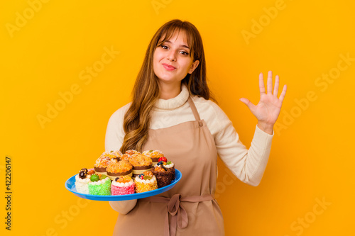 Young pastry chef woman isolated on yellow background smiling cheerful showing number five with fingers.