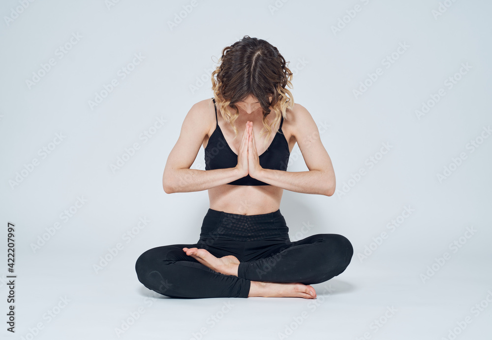 Woman sitting cross-legged on the floor joining hands yoga meditation asana