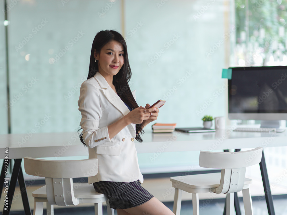 Businesswoman using smartphone and smiling to camera Businesswoman using smartphone and smiling to camera