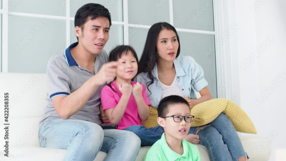 Happy asian family watching and cheering up football at home. Happy asian family watching and cheering up football at home.
