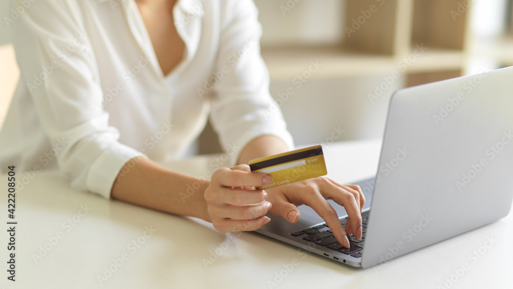 Female hand with credit card and typing on laptop keyboard while online shopping at home Female hand with credit card and typing on laptop keyboard while online shopping at home