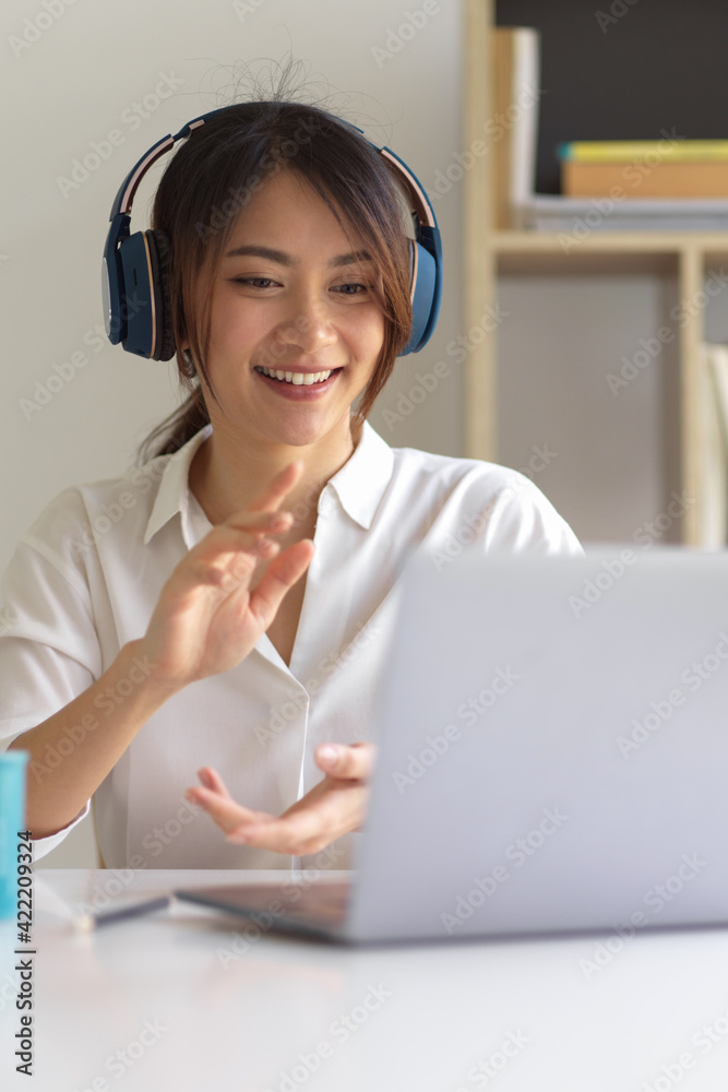 A woman with headphone talking with her colleagues while video conference A woman with headphone talking with her colleagues while video conference