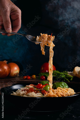 noodle pasta with black plate onion tomato basil tomato bread on dark base