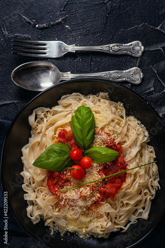 noodle pasta with black plate onion tomato basil tomato bread on dark base