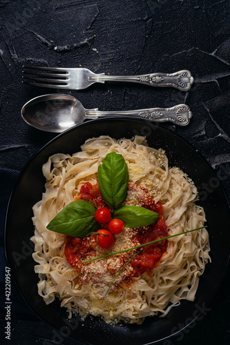 noodle pasta with black plate onion tomato basil tomato bread on dark base