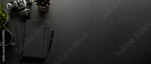 Dark creative workspace with notebook, pen, camera and copy space, creative mock up scene