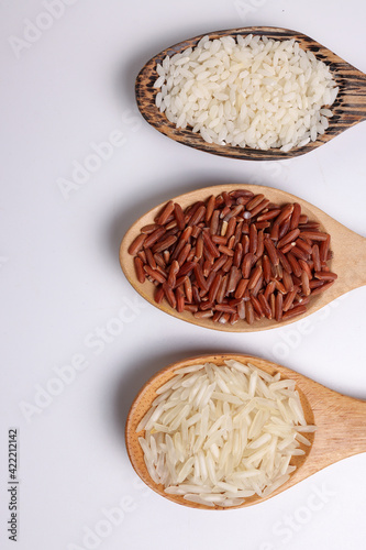 Long grain basmati medium grain jasmine short grain pilaf polau risotto brown low glycaemic index gi rice in wooden spoon on white background copy text space top flat lay view photo