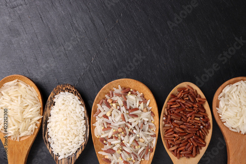 Long grain basmati medium grain jasmine short grain pilaf polau risotto brown low glycaemic index gi rice in wooden spoon on black background copy text space top flat lay view photo