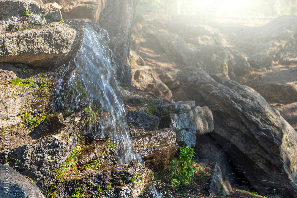 Mini waterfall, stream through stones, splashing water. Natural landscape.