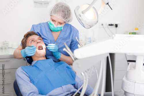 Dentist female in uniform is examinating of male in dental clinic. High quality photo