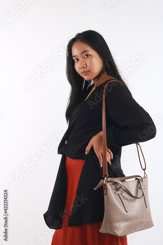 Young woman in casual outfit with stylish bag on white background.