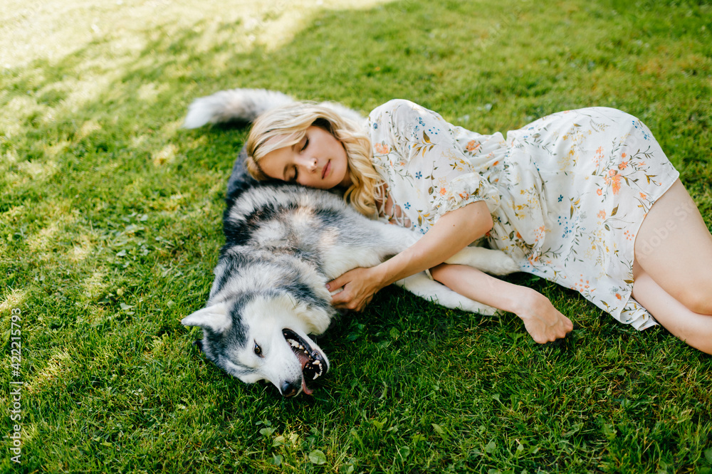 A young romantic woman lying with a dog on the grass A young romantic woman lying with a dog on the grass