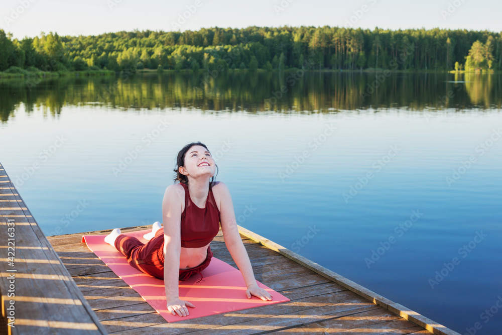 girl doing yoga on wooden pier by lake in summer girl doing yoga on wooden pier by lake in summer