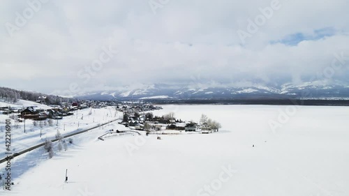 Flight above winter road and snow-covered lake. Aerial drone view. Beautiful winter landscape of countryside. South Ural, Bashkortostan, Russia. 4k photo